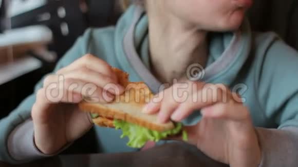 一位美丽的金发女人在咖啡馆里吃素食三明治和新鲜蔬菜视频的预览图