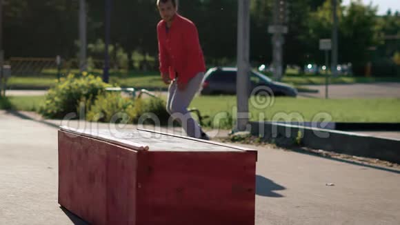 一个热爱自己爱好的成人滑板运动员跳在风扇箱上然后在街道滑板公园的一块木板上移动视频的预览图