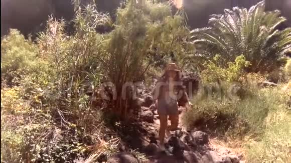 女孩正沿着一条山路在热带植物之间行走活动暑假的概念视频的预览图