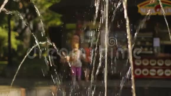 母亲带着蹒跚学步的孩子在城市公园的喷泉附近玩耍快乐的童年视频的预览图