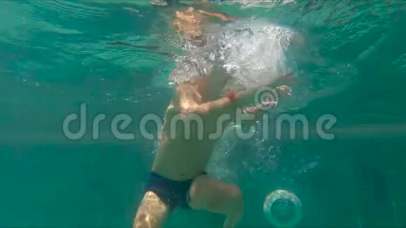 小男孩在游泳池里跳水和泼水的慢镜头视频的预览图