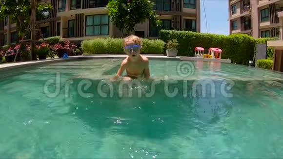 小男孩在游泳池里跳水和泼水的慢镜头视频的预览图