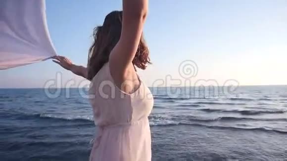 美丽的女人拿着轻盈的布料在海滩上享受日落视频的预览图