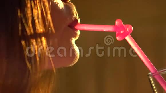 迷人的年轻女人通过打结的粉红色吸管喝酒4K特写视频视频的预览图