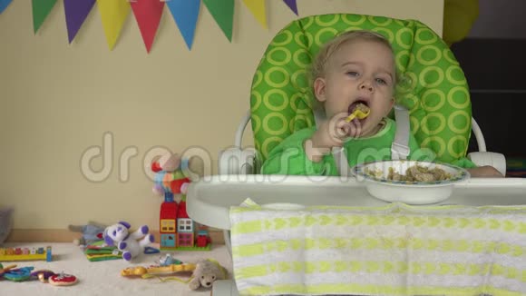 宝宝坐在高椅子上用勺子盘子和玩具等着宝宝视频的预览图
