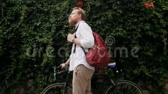 4k视频时尚小胡子男子提着包在街上骑自行车散步视频的预览图