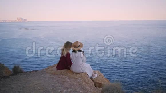 两个朋友坐在岩石上看日落视频的预览图