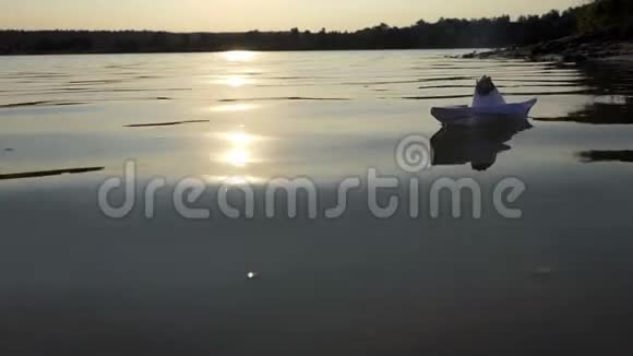 夕阳西下一只幼稚的纸船在湖水中畅游视频的预览图