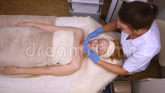 美容师在客户的皮肤上涂上奶油顶部视图视频的预览图