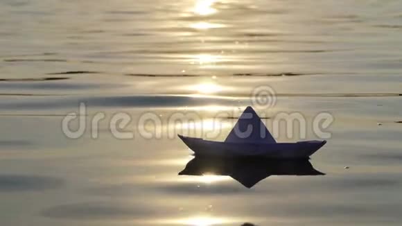 夕阳西下一只可爱的纸船漂浮在森林湖里视频的预览图
