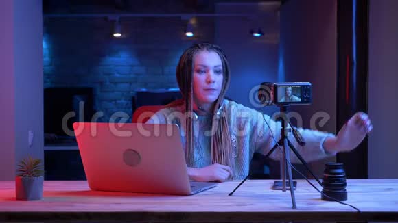 一位年轻迷人的女性博客写手戴着可怕的耳机用霓虹灯玩电子游戏视频的预览图