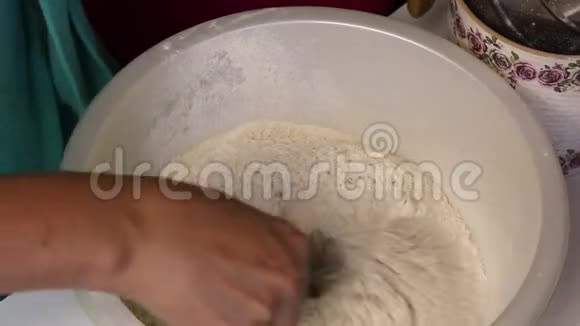 整粒面粉筛入盆中一个女人加了一杯矿泉水为了揉面团视频的预览图