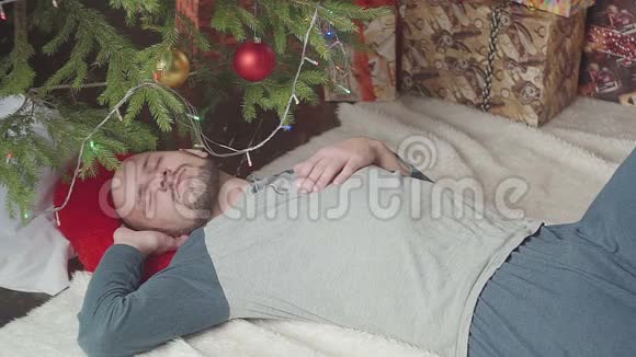 圣诞树附近一个熟睡的年轻人视频的预览图