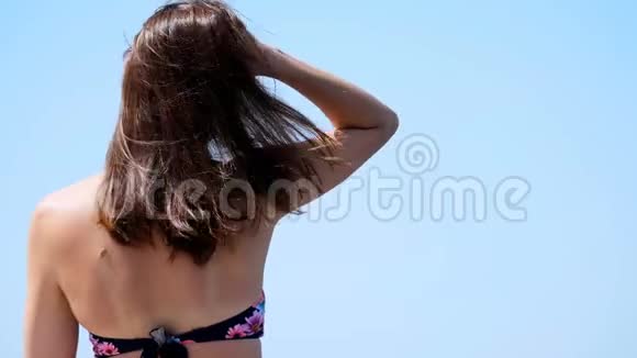 夏天大海从后面的肖像美丽的年轻黑发女人穿着泳衣和太阳镜享受着视频的预览图