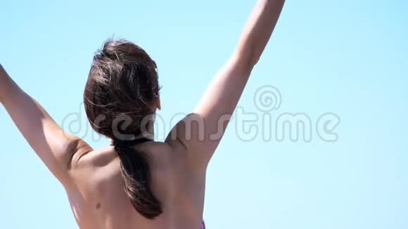夏天大海从后面的肖像美丽的年轻黑发女人穿着泳衣和太阳镜享受着视频的预览图