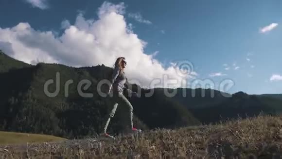 山云背景下的少女旅人一个带背包的游客上坡视频的预览图