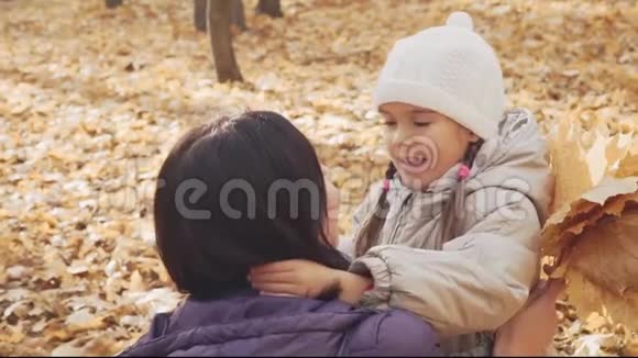 快乐的小女孩在秋天公园拥抱她的母亲视频的预览图