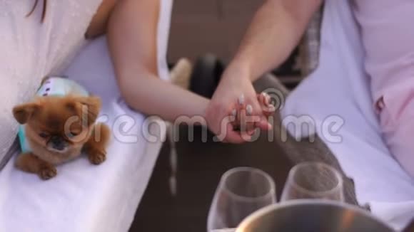 不知名的情侣正温柔地牵着手在日光浴床上晒太阳桌上放着香槟可爱可爱视频的预览图