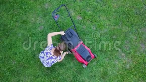 年轻女子用割草机在自家后院割草4K视频的预览图