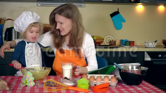 爱的母亲和她兴奋的可爱女儿女孩在厨房里筛面粉视频的预览图