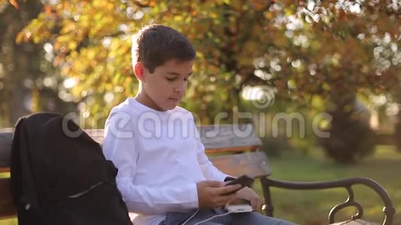 穿着白衬衫的少年用powerbank给他的智能手机充电智能手机低电池视频的预览图