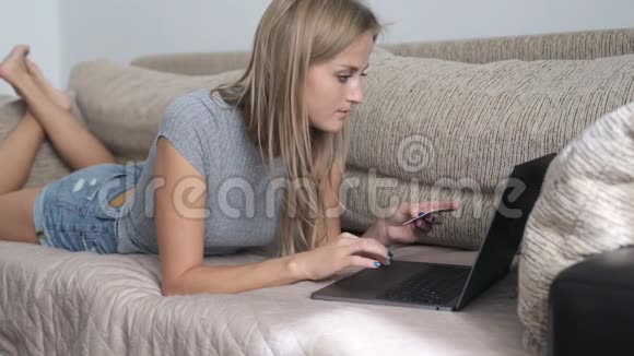 年轻女子拿着信用卡在笔记本电脑上打字视频的预览图