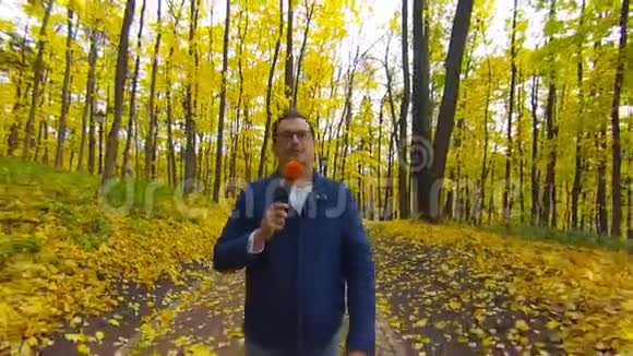 快乐新闻记者正在秋天公园为电视报道视频的预览图