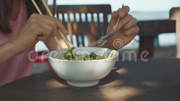 母女俩在露天海滩咖啡馆用筷子吃面条汤视频的预览图