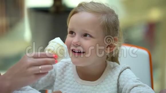 那个金发女孩有趣可爱的小女孩在大购物中心吃冰淇淋和喇叭一家人吃冰淇淋视频的预览图