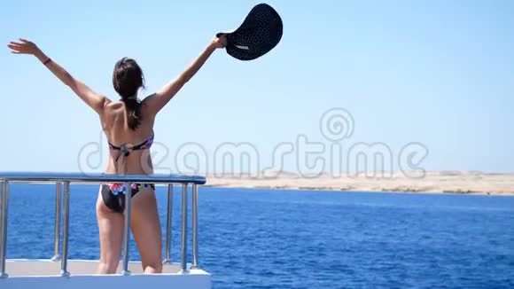 夏天大海美丽的年轻黑发女人穿着泳衣戴着太阳帽站在渡船甲板上视频的预览图