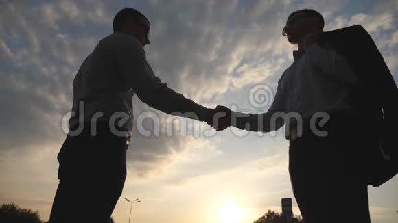 两个年轻的商人互相问候背景是多云的天空户外商务握手男性晃动视频的预览图