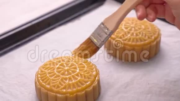 中秋节制作月饼的过程妇女在烘焙前在糕点表面刷蛋液节日自制视频的预览图