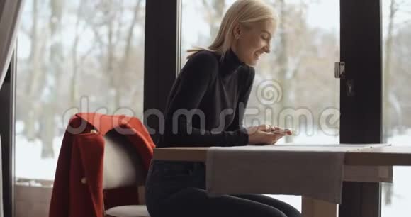 年轻的女人在等咖啡的时候用电话视频的预览图
