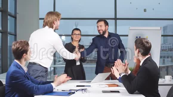 商务人士在面试时握手而其他人则在办公室拍手视频的预览图