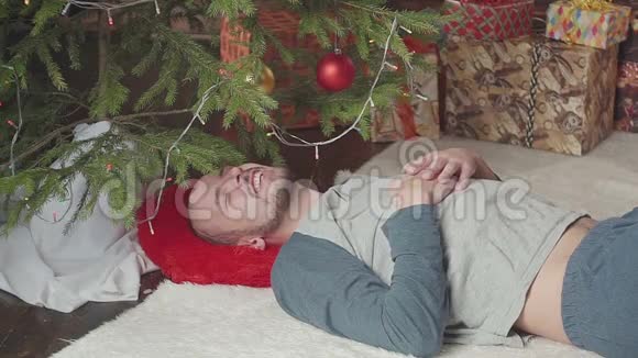 圣诞树附近一个熟睡的年轻人视频的预览图