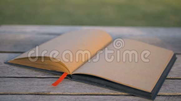 风把躺在长凳上的一本空白书的书页吹翻了非常漂亮的设计师笔记本在街上视频的预览图