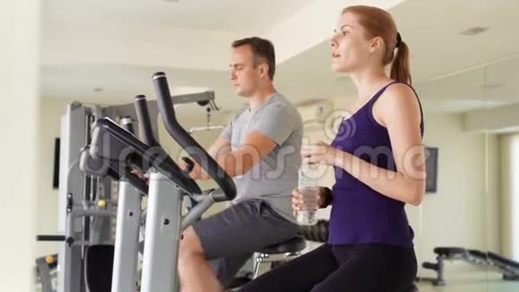 适合运动积极的夫妇在健身房锻炼自行车塑料瓶饮用水视频的预览图
