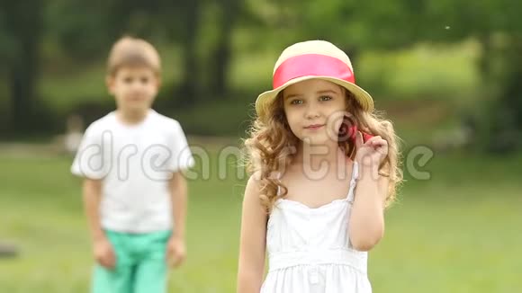 小女孩站在公园里她身后是一个小男孩慢动作视频的预览图