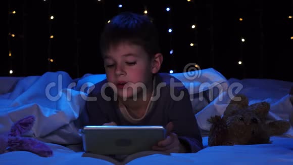 小男孩躺在床上拿着笔记本电脑看着一幅漫画博克背景视频的预览图