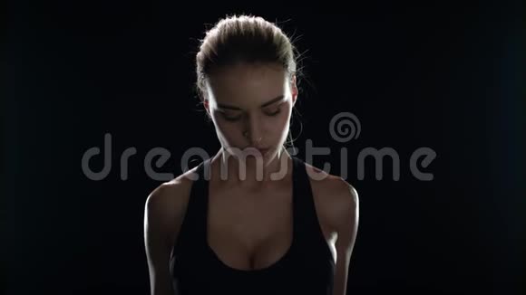运动女性在黑暗健身房锻炼时用哑铃训练视频的预览图