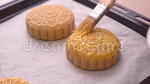 中秋节制作月饼的过程妇女在烘焙前在糕点表面刷蛋液节日自制视频的预览图