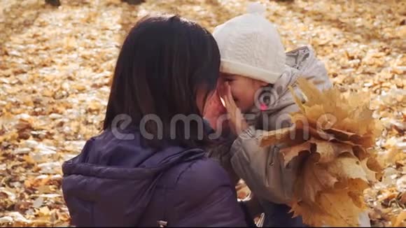 快乐的小女孩在秋天公园拥抱她的母亲视频的预览图