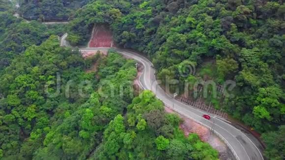 台湾绿树林中的汽车沿着弯曲的蛇形道路行驶鸟瞰图视频的预览图
