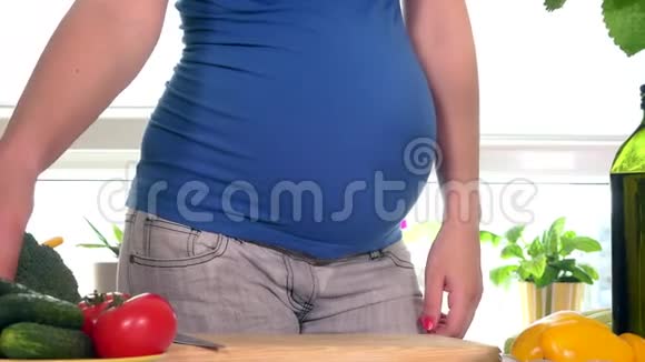 怀孕少女的胃和手用刀子切红辣椒水果做沙拉视频的预览图