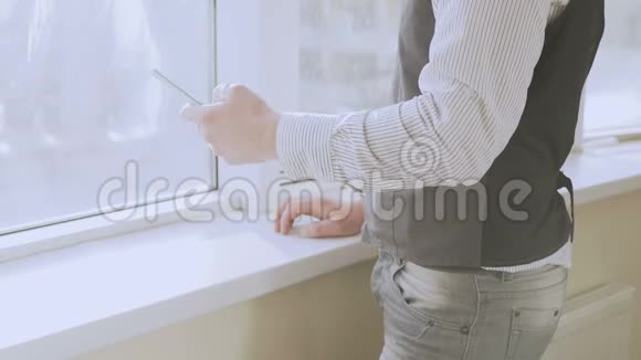 男生站在窗边从智能手机发短信找工作视频的预览图