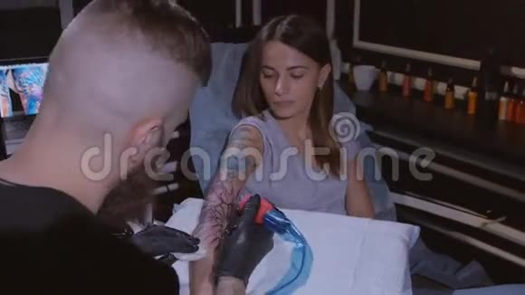 纹身师在工作室做纹身特写专业纹身师在一个年轻女孩手上纹身视频的预览图
