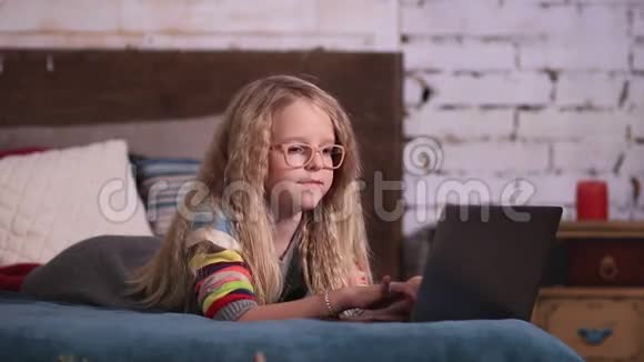 可爱的小女孩在床上玩手提电脑视频的预览图