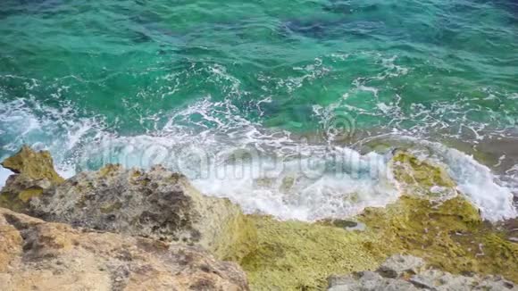 晴天鸟瞰绿松石海在缓慢运动中溅到岩石上的海浪的俯视图视频的预览图