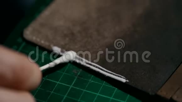 手工制作皮夹的过程工匠在皮夹的皮件上涂上胶水视频的预览图