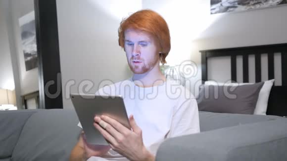 红发男子在卧室使用平板电脑造成的损失视频的预览图